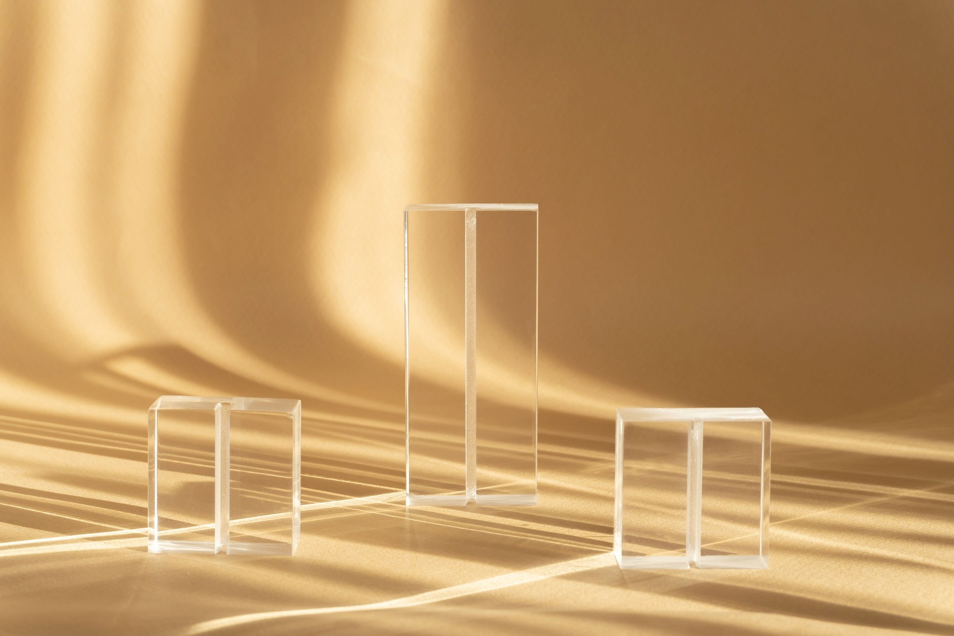Glass prisms of various heights with complex reflection and hard shadows on beige background. 3d stands for demonstration of cosmetic products
